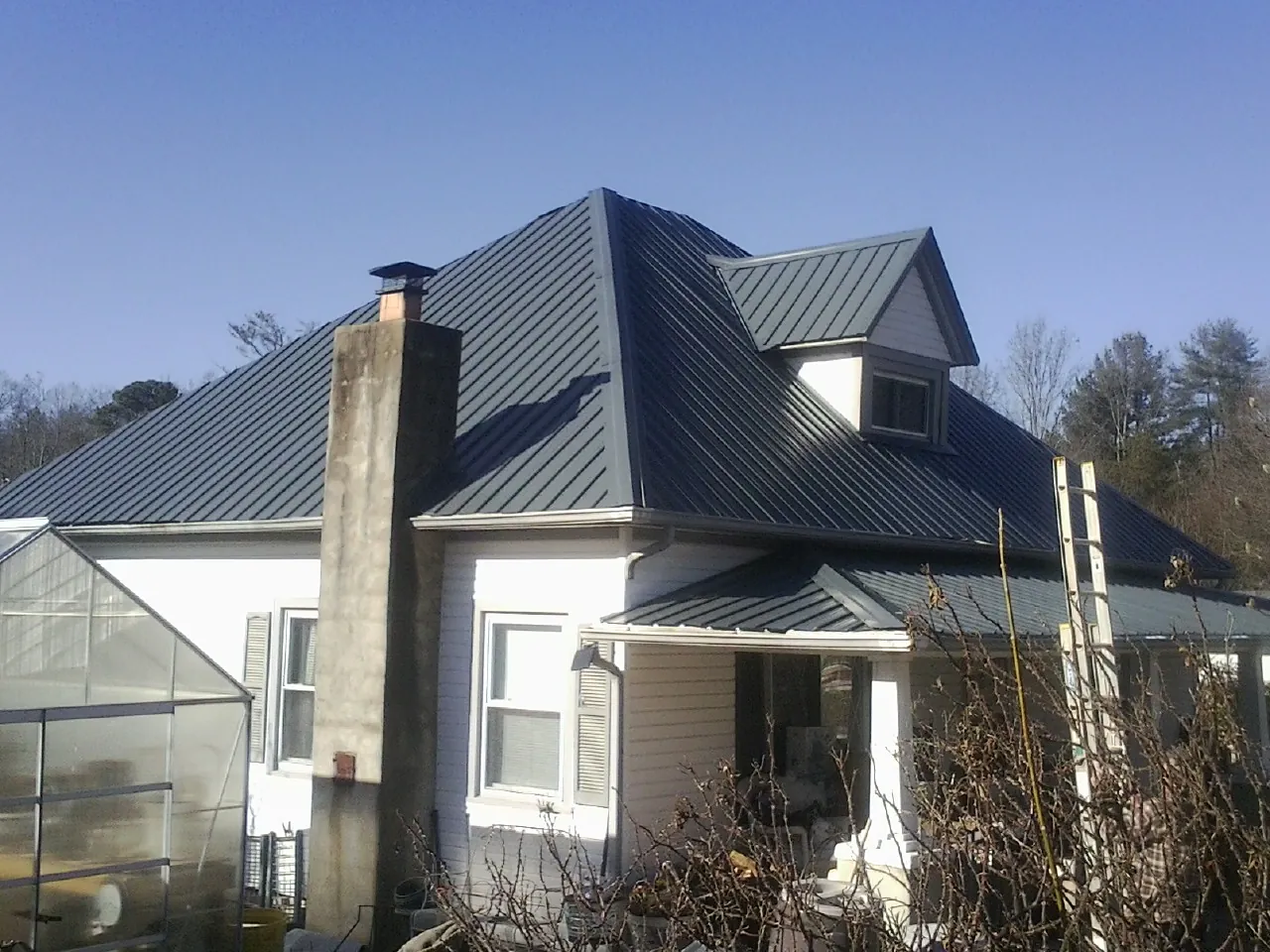 Dark blue standing seam metal roof on a white farmhouse with dormer — Slate & Tile Roof Repair by Roofing Brothers in Kittery Point