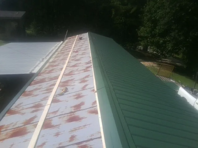 Old rusted panels beside newly installed green metal roofing — Wind Damage Roof Repair by Roofing Brothers in Kittery Point