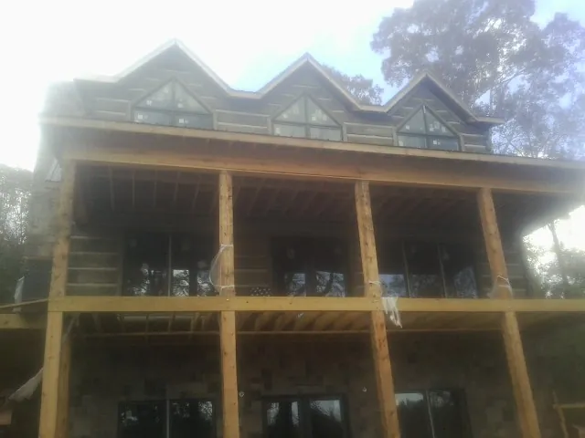 Dormers and porch framing on a large log home under construction — Roof Coating work by our crew in Kittery Point