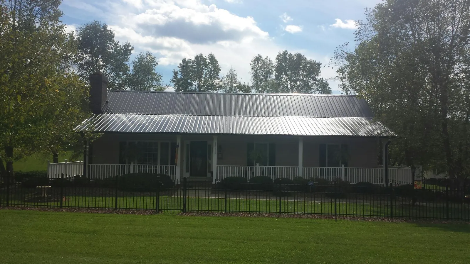 Gray metal roof on a brick ranch with a full width front porch — Gutter Guard Installation work by our crew in Kittery Point