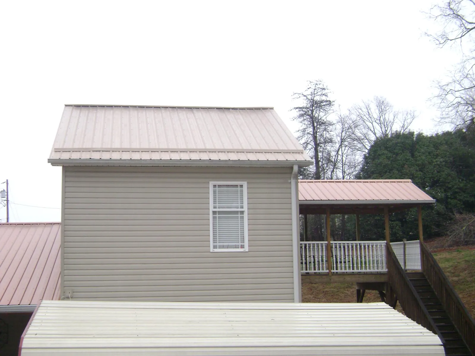 Tan metal roofs on a two story addition and attached porch, from a Roof Replacement job in Kittery Point