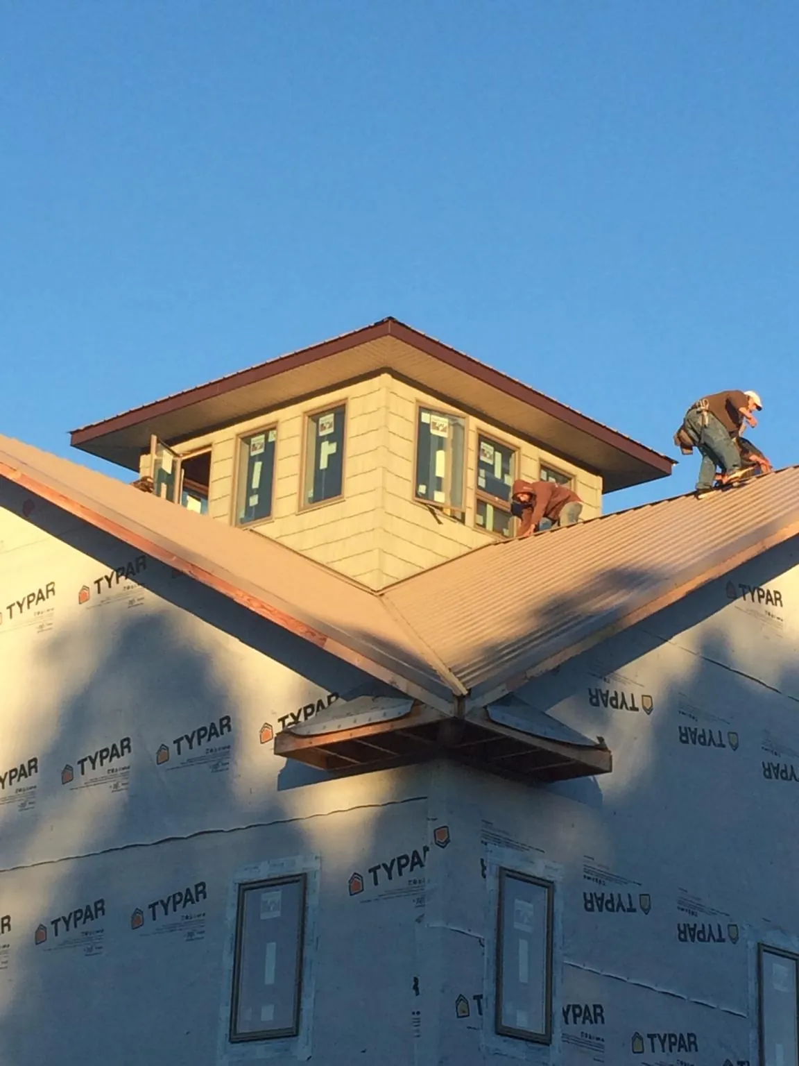 Roofers working around a rooftop cupola on a new metal roof at sunset — Roof Waterproofing in Kittery Point by Roofing Brothers